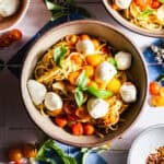 Bowls of blistered cherry tomato pasta with mozzarella and basil.