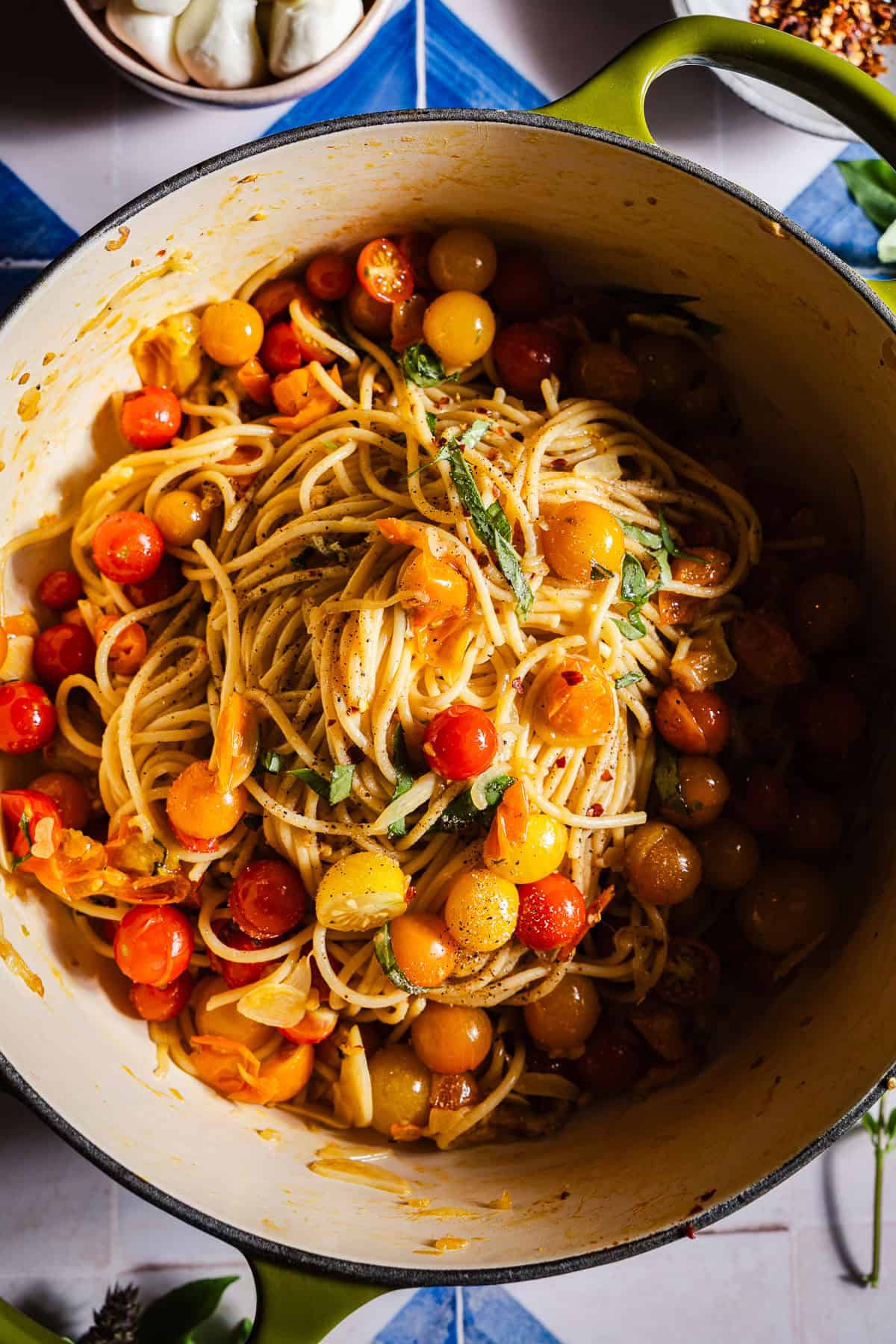 A dutch oven with spaghetti tossed in blistered cherry tomato sauce.