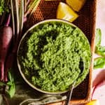 A bowl with carrot top pesto in a basket with the ingredients.