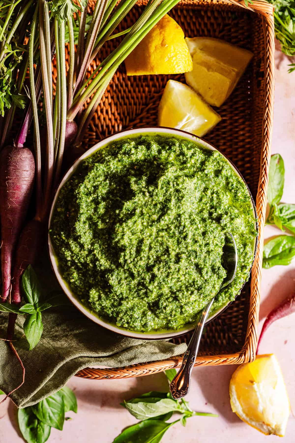 A bowl with carrot top pesto in a basket with the ingredients.