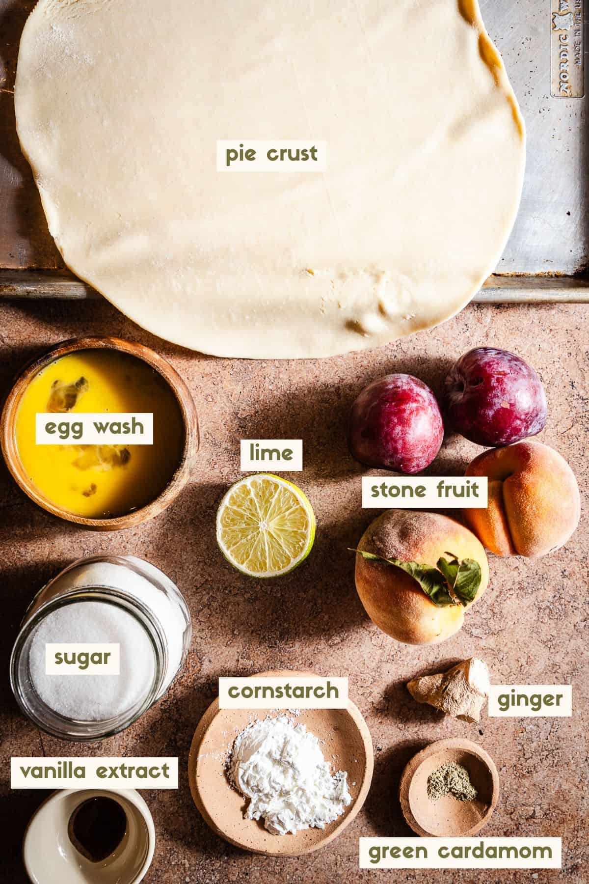 Pie crust, egg wash, lime, stone fruit, sugar, vanilla extract, cornstarch, ginger, green cardamom ingredients with labels.