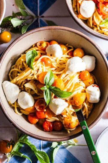 Bowl of blistered cherry tomato pasta with mozzarella and basil.