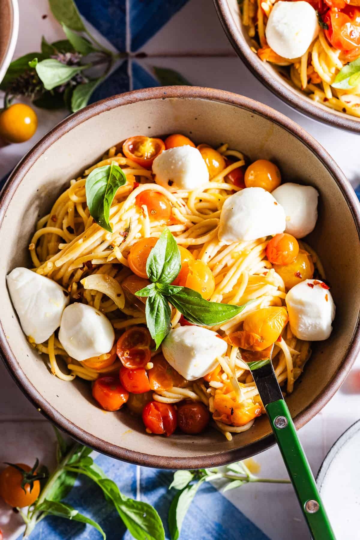 Bowl of blistered cherry tomato pasta with mozzarella and basil.