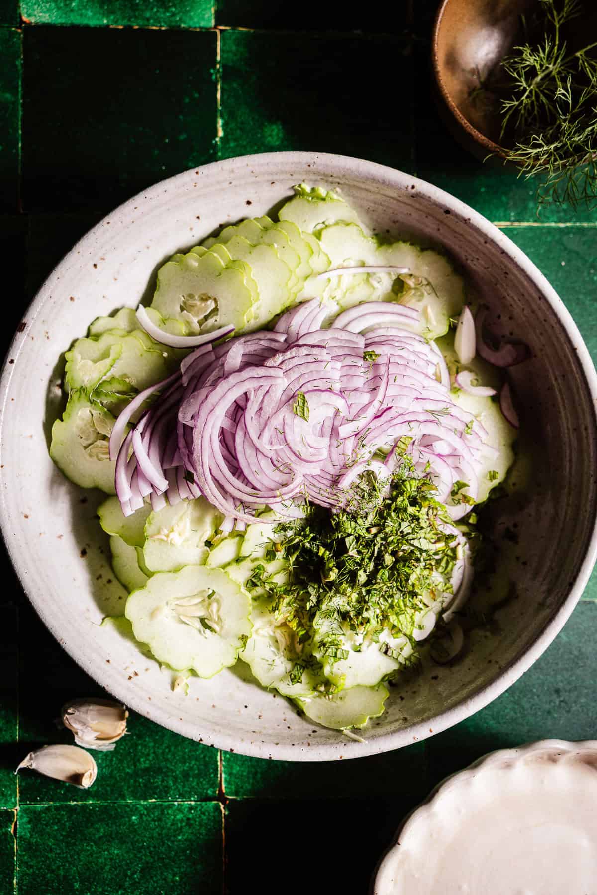 Sliced cucumbers with red onion and chopped herbs.