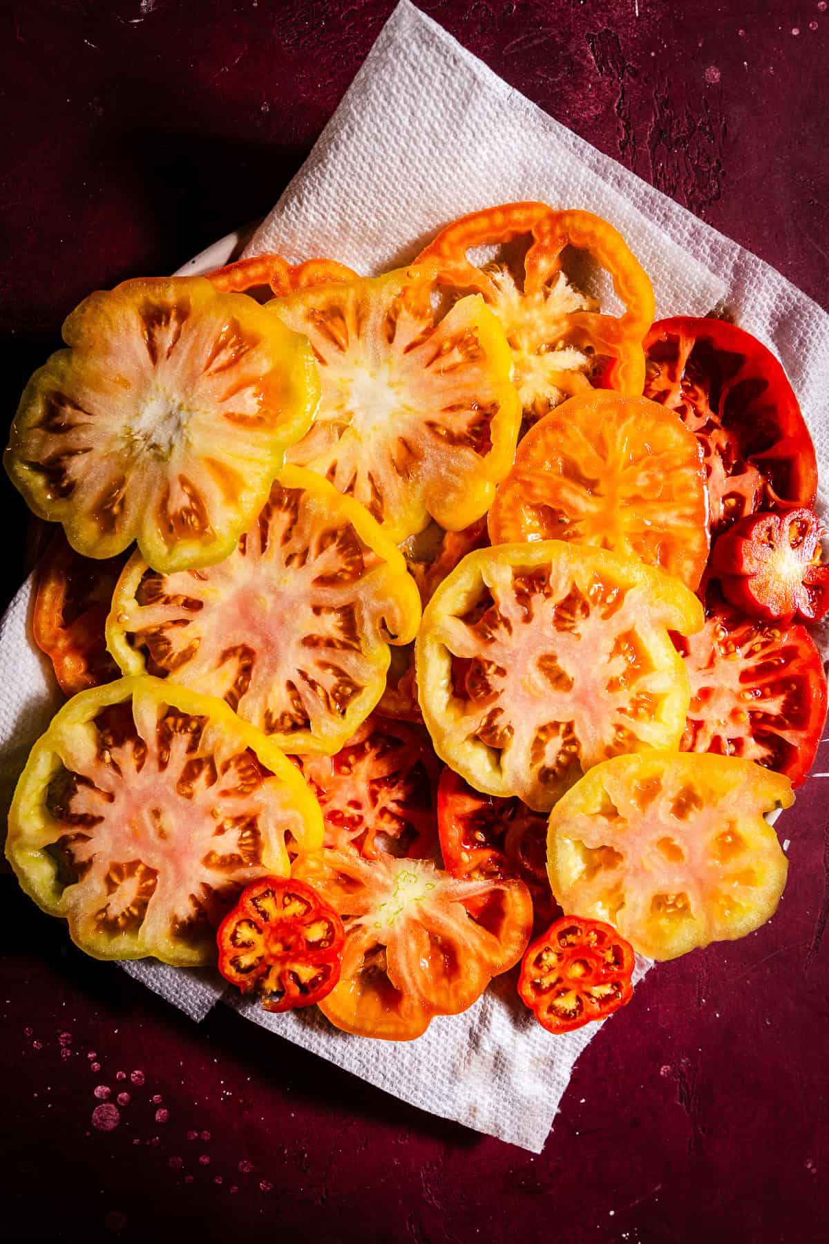 Sliced heirloom tomatoes salted and draining on paper towels.