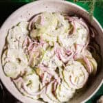 A bowl of sliced cucumbers with onions and dill.