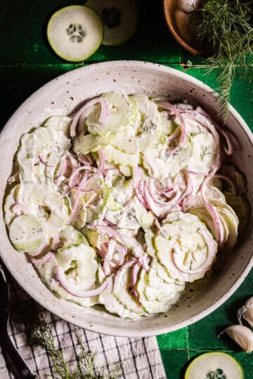 A bowl of sliced cucumbers with onions and dill.